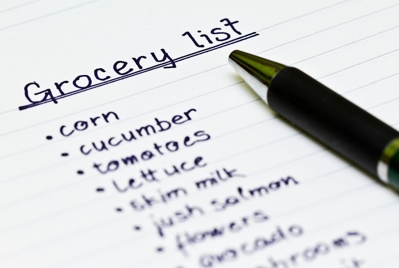A written grocery list with a pen.