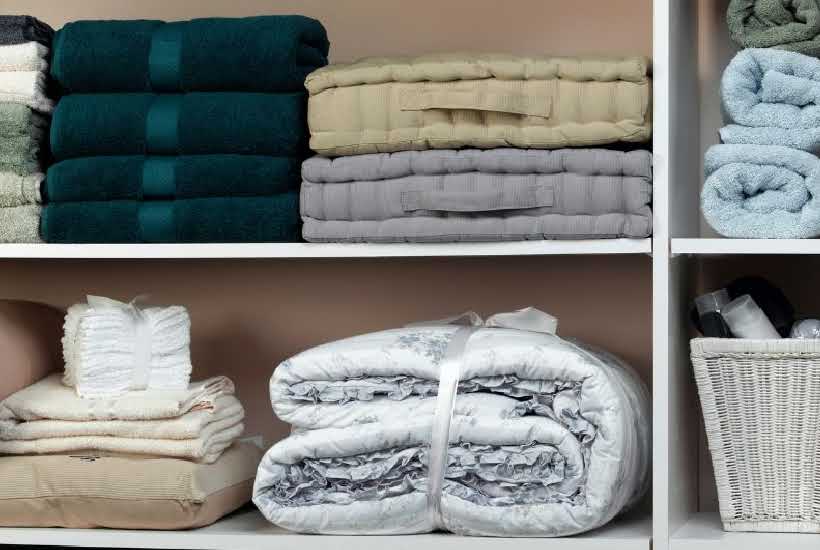 interior view of a linen closet with folded sheets and towels.