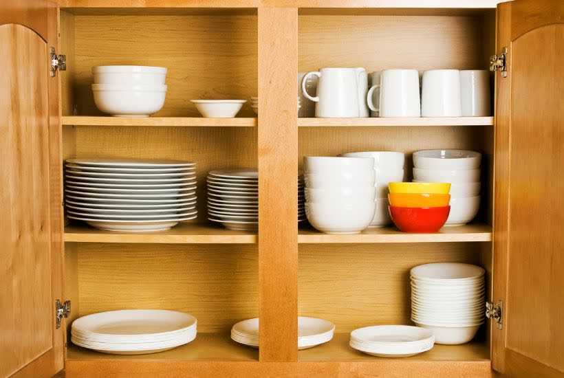 inside view of a cabinet filled with plates, bowls and coffee cups.
