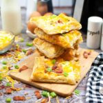 Air fried puff pastry egg tarts stacked on a wood cutting board.
