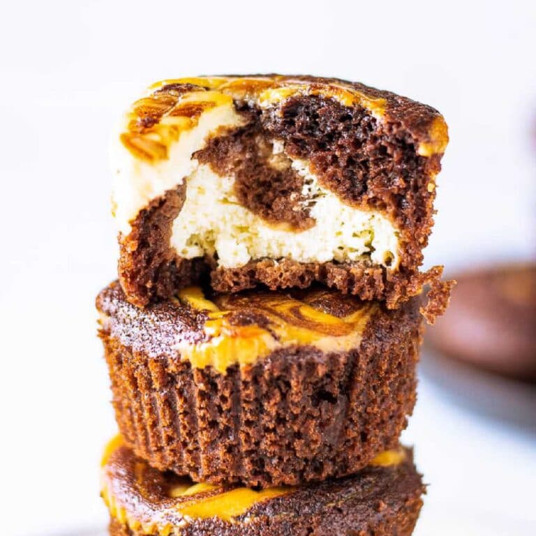 close up of stacked chocolate cheesecake muffins with a bite from the top one