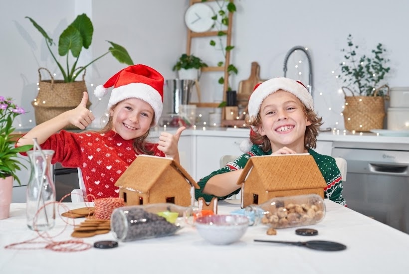 A boy and girl making gingerbread houses.