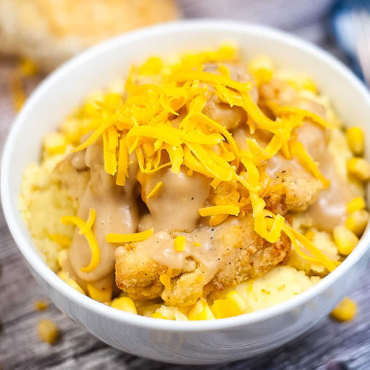 close up of homemade kfc famous bowl topped with shredded cheddar cheese.