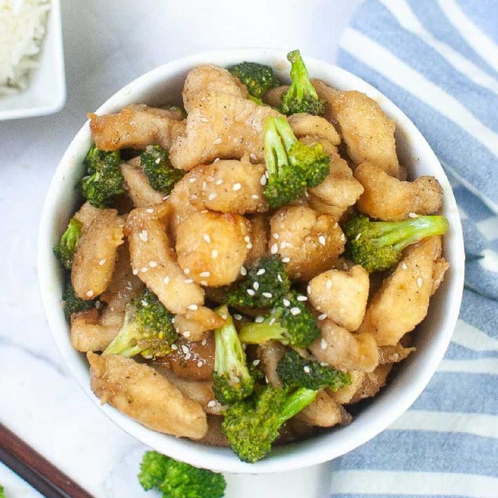 White bowl filled with chicken and broccoli made in the air fryer.