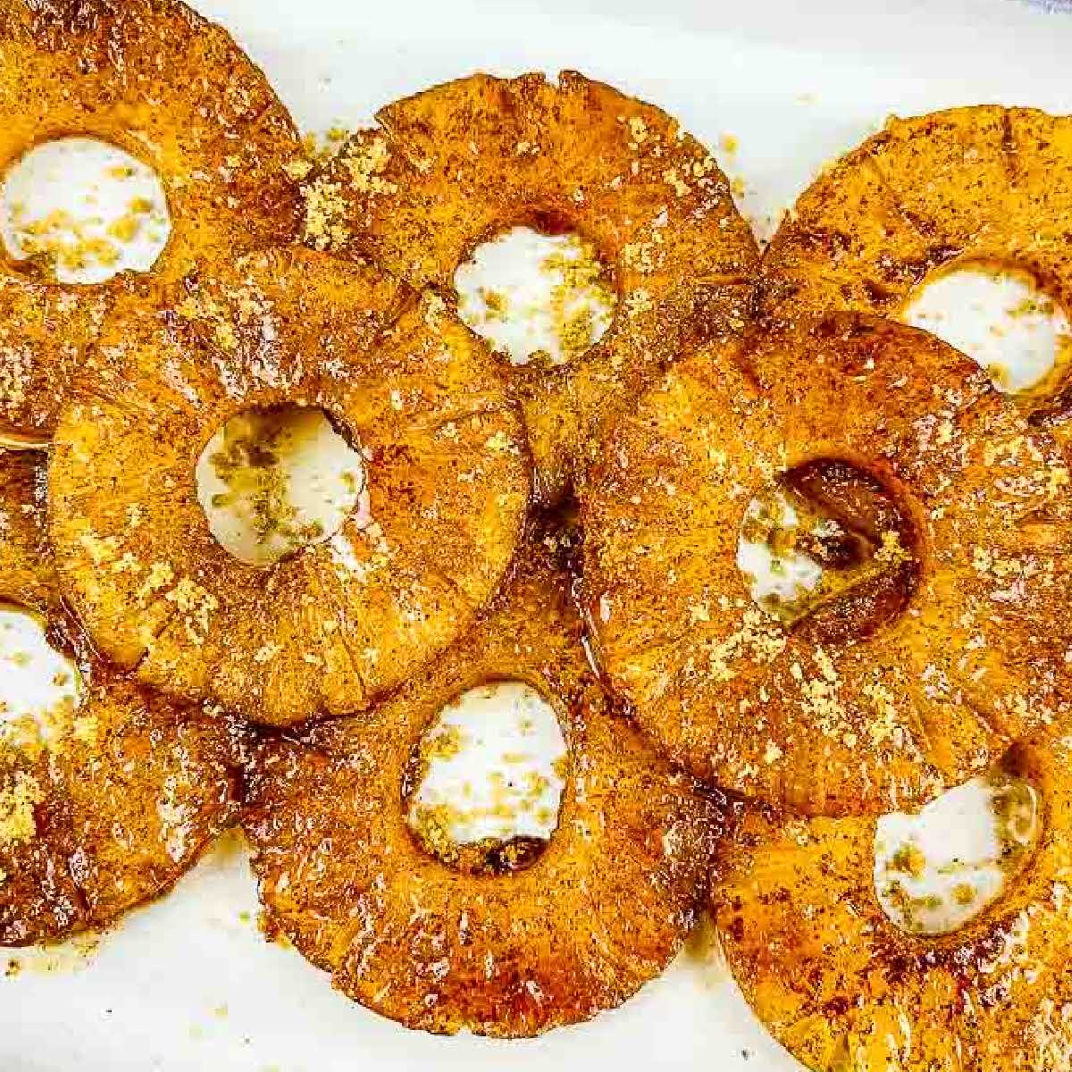 closeup view of air fryer pineapple rings on a white serving dish.