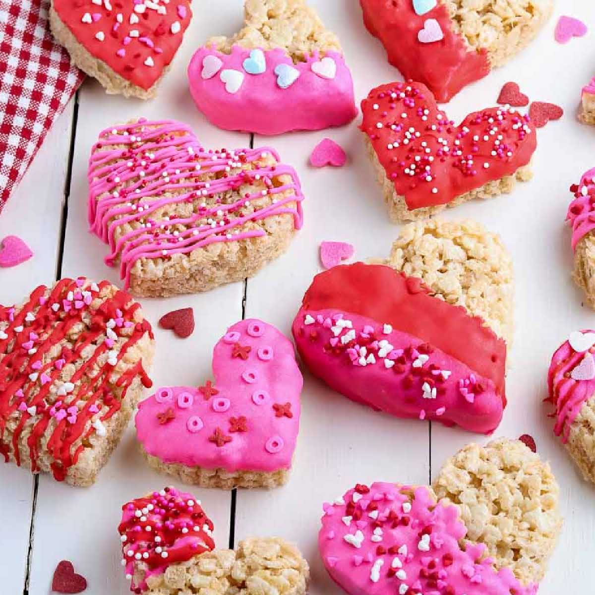 top view of decorated heart shaped rice krispie treats on a white wood background.
