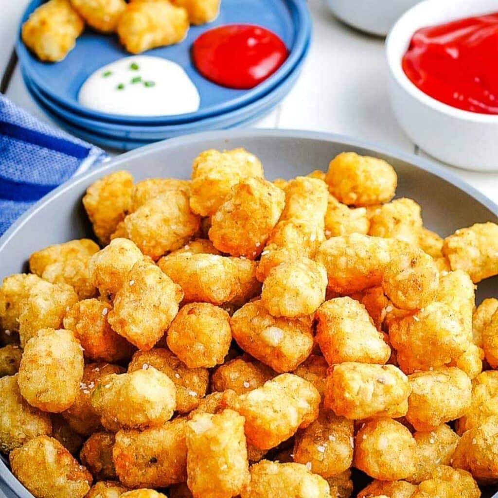 tater tots on plate after cooking in the air fryer next to ramekin of ketchup