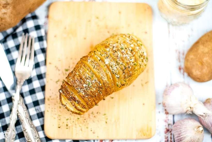 top shot of an air fried accordion potato on a small cutting board next to fork.