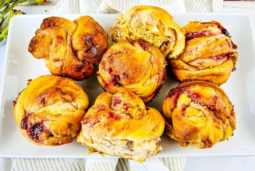 Overhead view of raspberry cream cheese cruffins on a white rectangular platter.