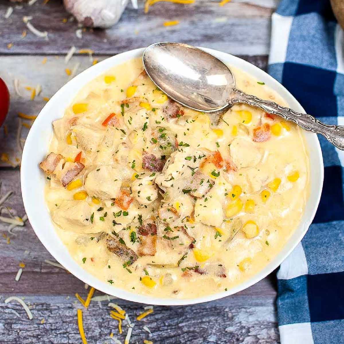 Overhead view of Instant Pot Chicken Corn Chowder with bacon in a white bowl with a spoon.