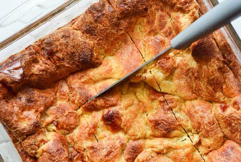 cutting a casserole dish of bread pudding into slices.