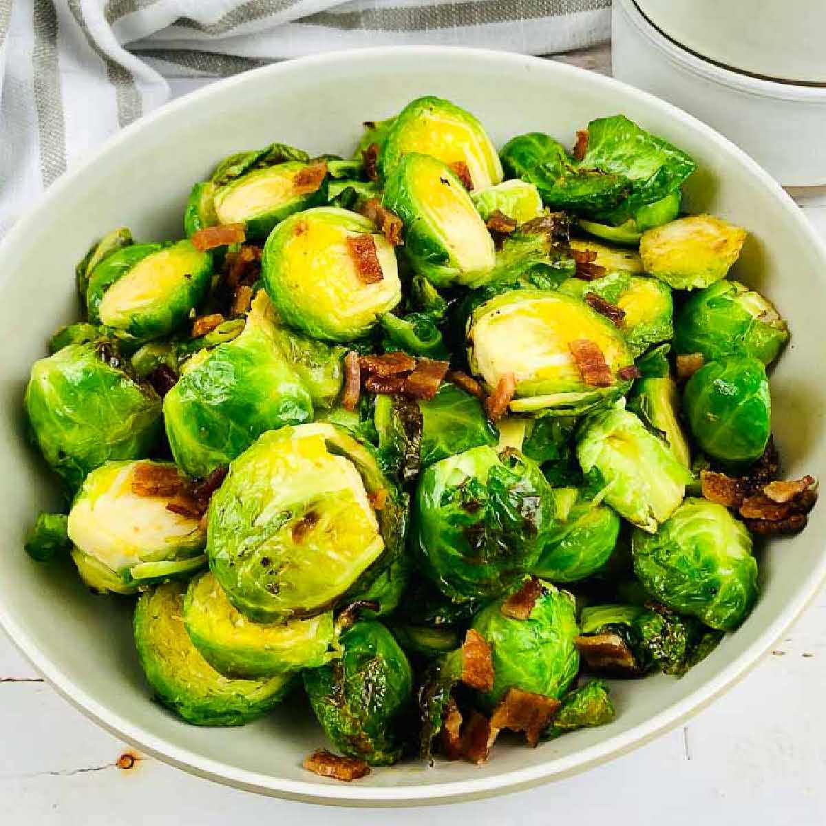 air fryer brussels sprouts with bacon and maple in a large white bowl.