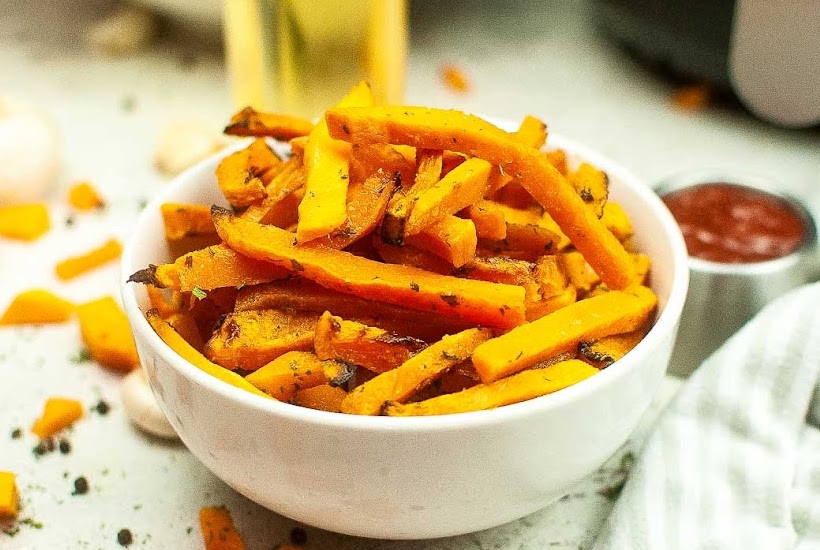 small bowl of air fried butternut squash fries with ketchup dipping sauce.