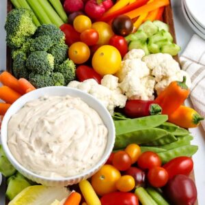 crudite board filled with fresh veggies and a bowl of creamy dip.