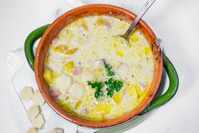 Overhead view of crockpot Ham and Potato Soup in a bowl with a white background.