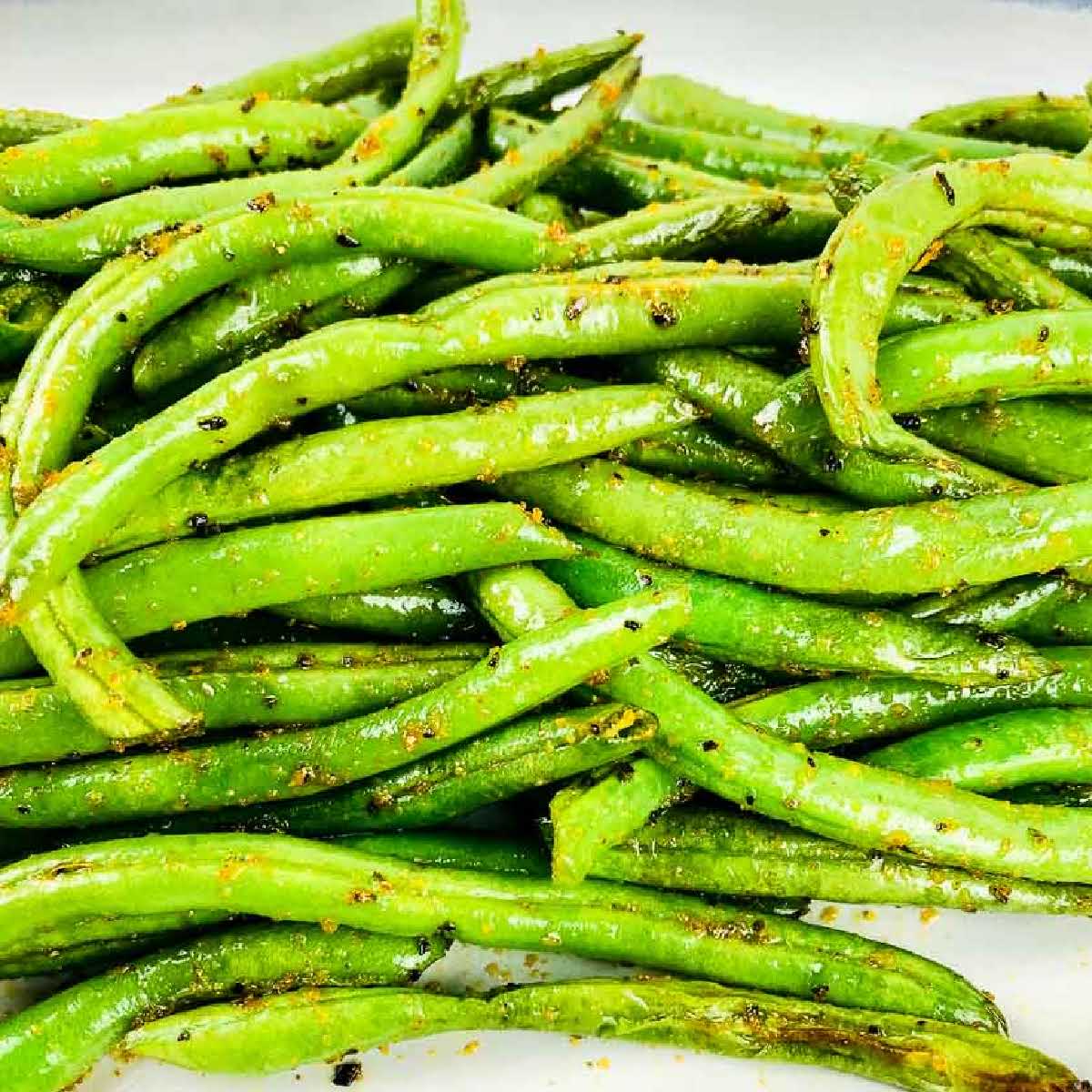 Closeup view of air fryer crispy green beans on a white plate.