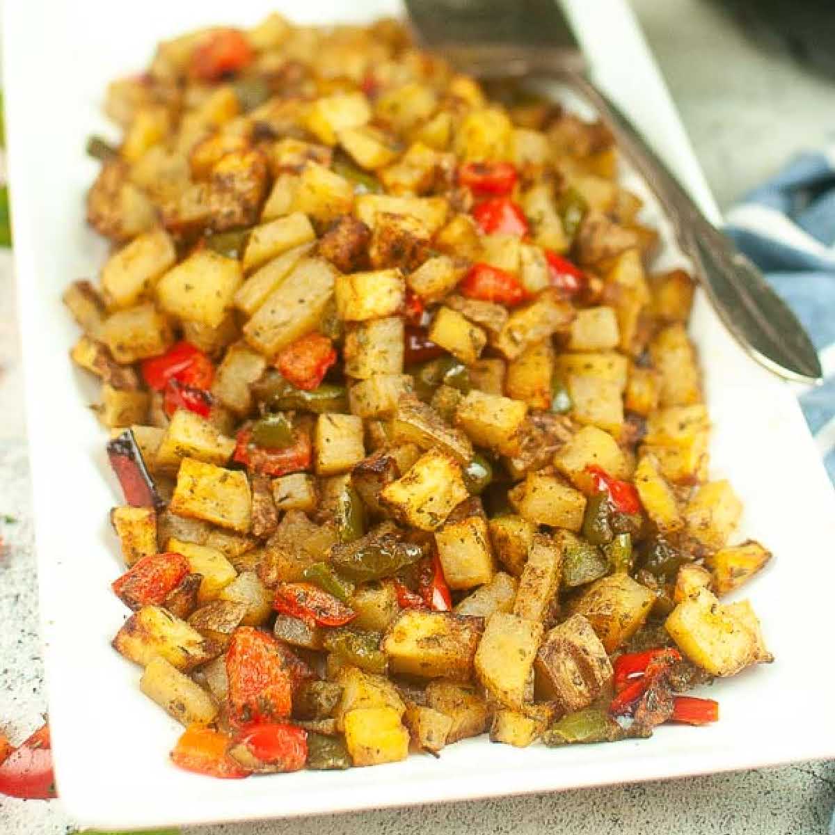 Air fryer breakfast potatoes and peppers on a white platter.