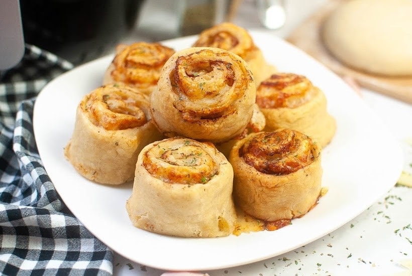 Close up view of air fryer pinwheels on a white plate.