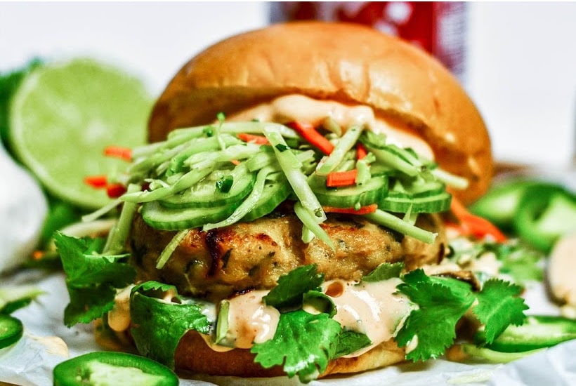 Front close up view of Asian Chicken Burger with a cut lime in the background.