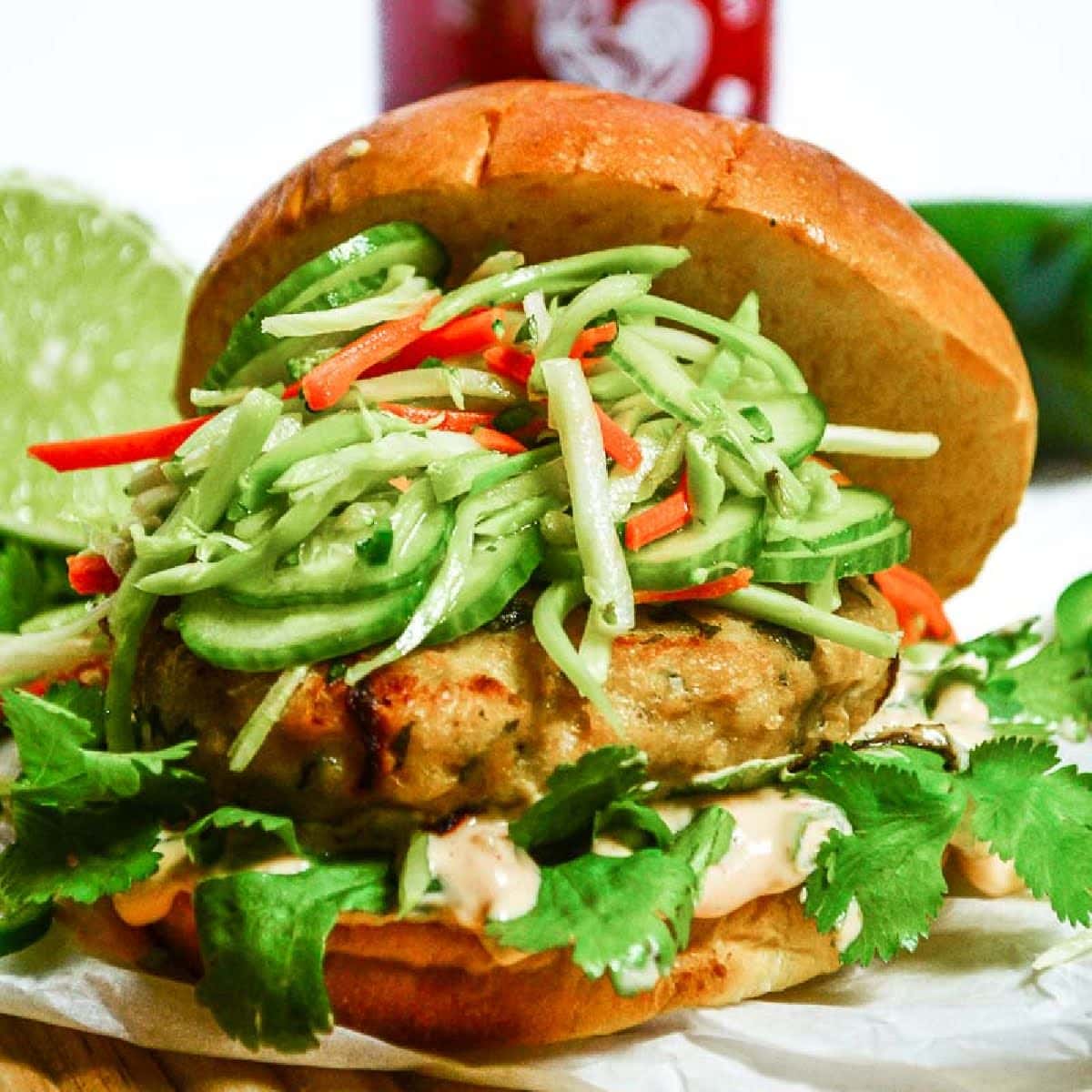 Asian Chicken Burger topped with slaw with the bun leaning off the side.