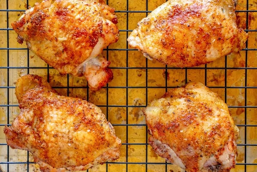 Overhead view of crispy baked chicken thighs on a cooling rack.