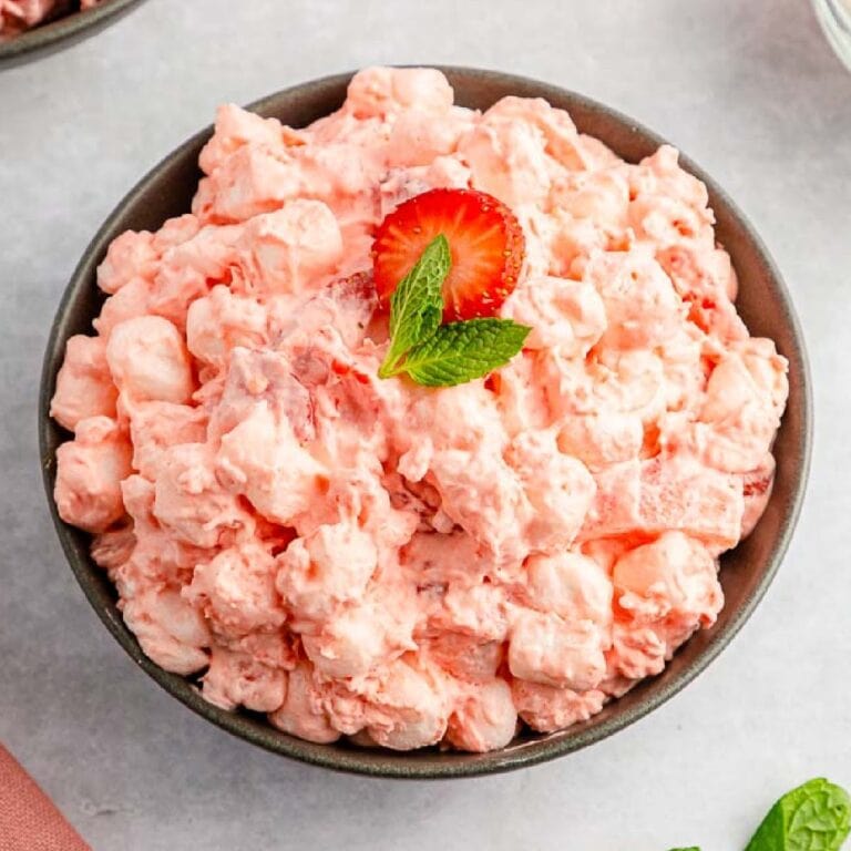 Overhead view of a bowl of Strawberry Fluff Salad with mint and a strawberry.