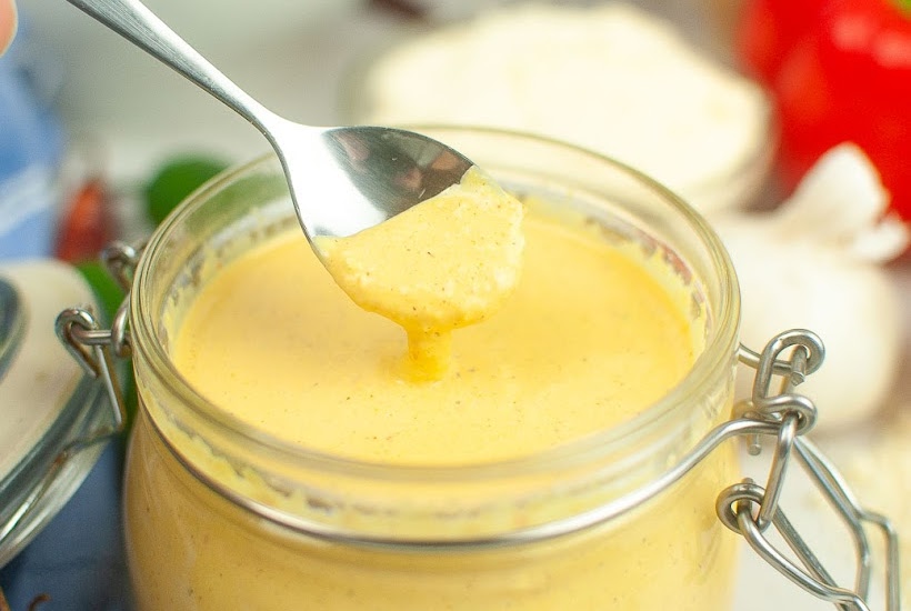 Closeup view of spoonful of creamy Baja sauce being removed from the jar.