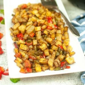 Air fried breakfast potatoes and peppers on a white platter.