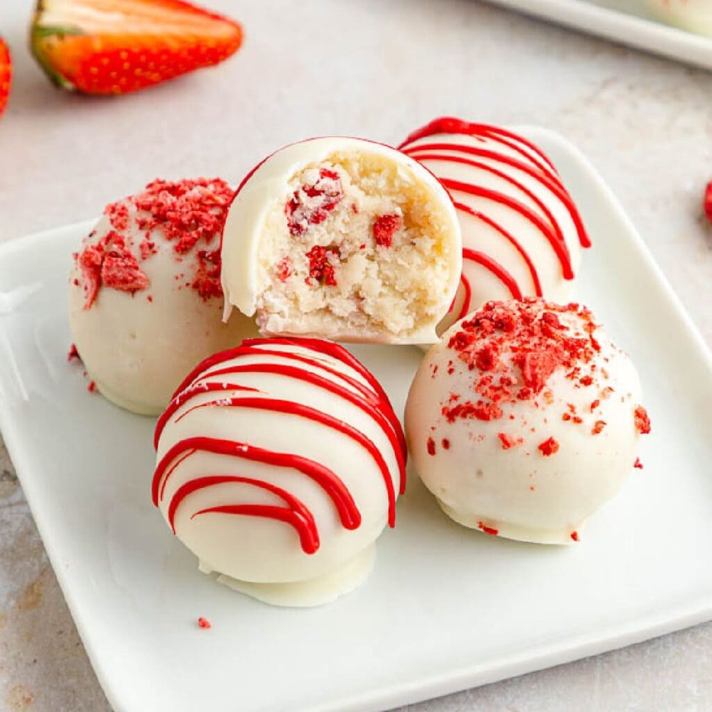 Strawberry Cake Balls on a small dish a bite taken from one.