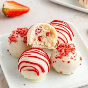 Strawberry Cake Balls stacked on a plate with a bite taken from the top one.