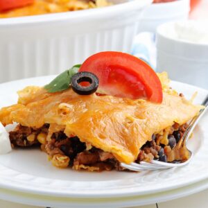A slice of Walking Taco Casserole on a small white dish with a fork.