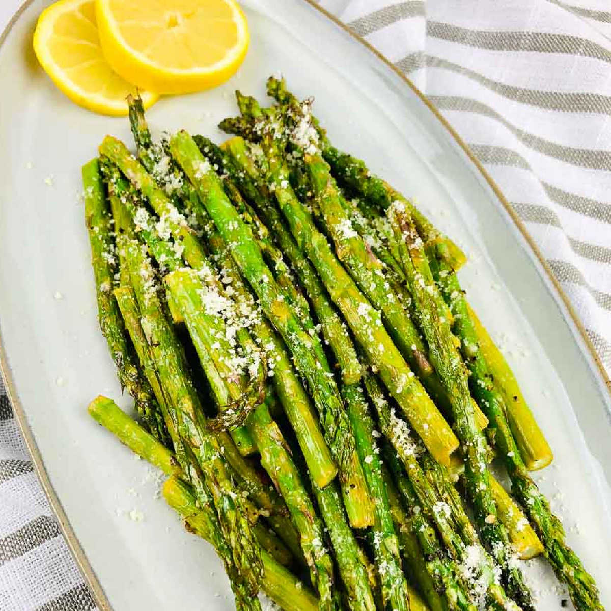 Air fried asparagus garnished with parmesan and lemon slices with text overlay.