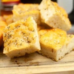 Slices of air fried focaccia bread on a wood cutting board.