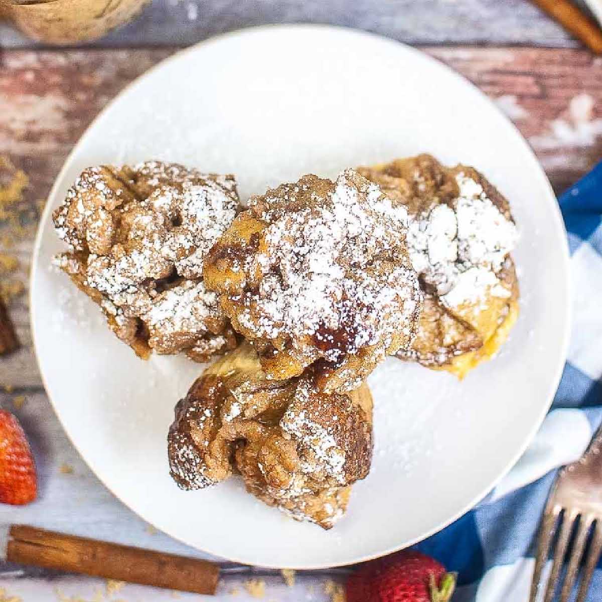 Overhead view of Air Fryer French Toast Muffin Cups dusted with powdered sugar on a plate.