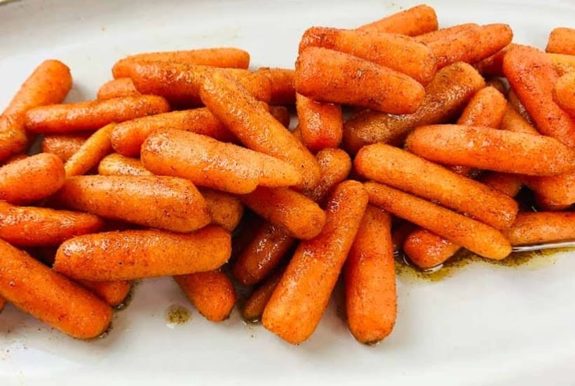 Close up view of air fryer roasted carrots on a white platter.