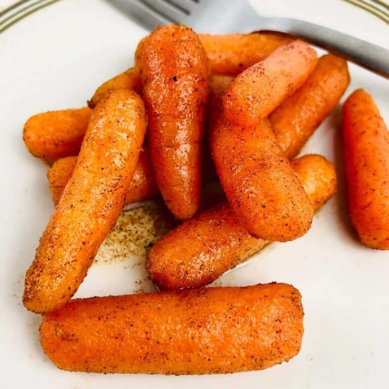 Air fryer glazed carrots on a white plate next to a fork.