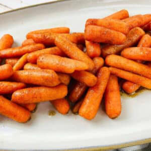 Close up view of air fried carrots with brown sugar glaze on a white platter.