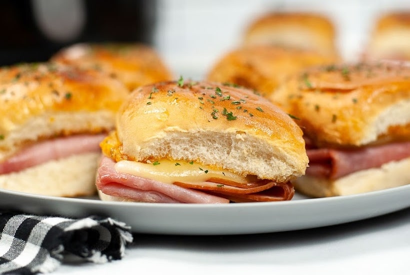 Close up view of air fried ham and Swiss sliders on a plate.