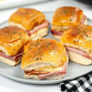 Five ham and Swiss cheese air fried sliders on a plate.