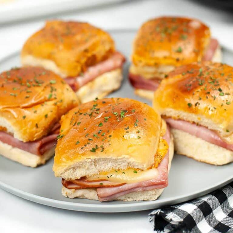 Five ham and Swiss cheese air fried sliders on a plate.