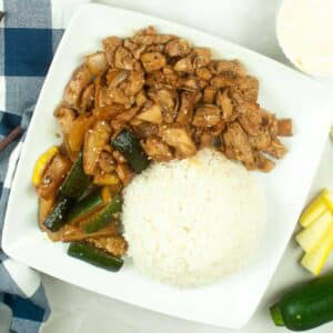Overhead view of air fryer hibachi chicken and vegetables on a plate with a scoop of white rice.