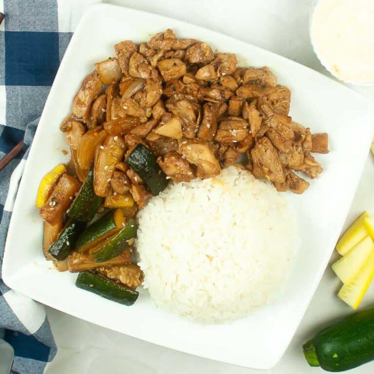 Overhead view of air fryer hibachi chicken and vegetables on a plate with a scoop of white rice.