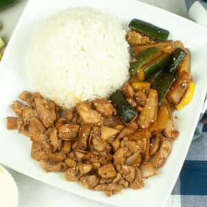 Overhead view of a white plate filled with hibachi chicken and vegetables with a scoop of white rice.