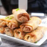 Air fried pork egg rolls stacked on a white plate.
