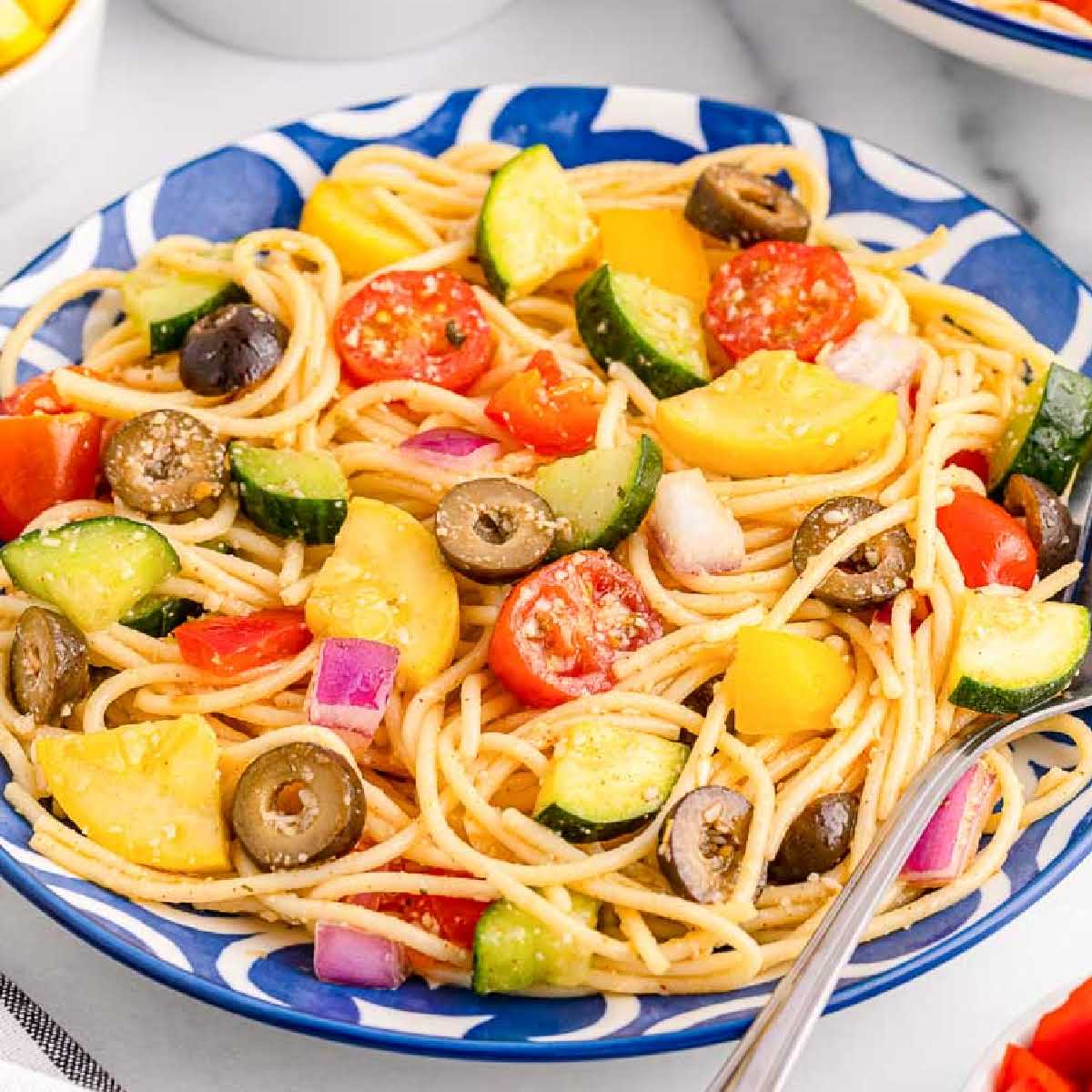 Front view of a bowl filled with California Spaghetti Salad with a fork in it.