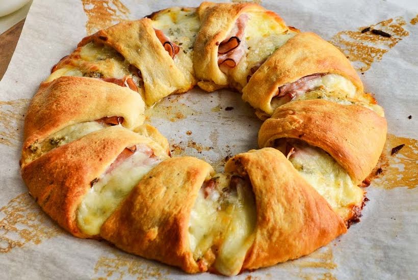 Baked Pillsbury crescent ham and cheese ring on parchment paper.