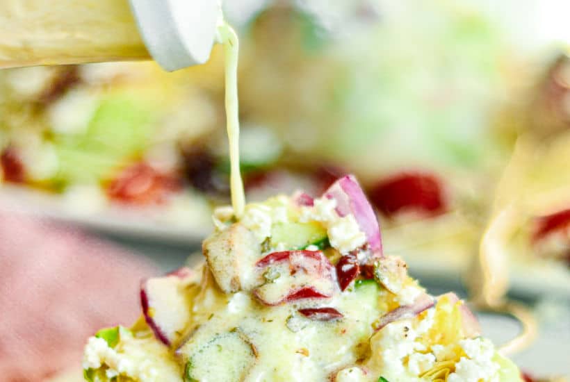 Dressing being poured on a salad wedge.