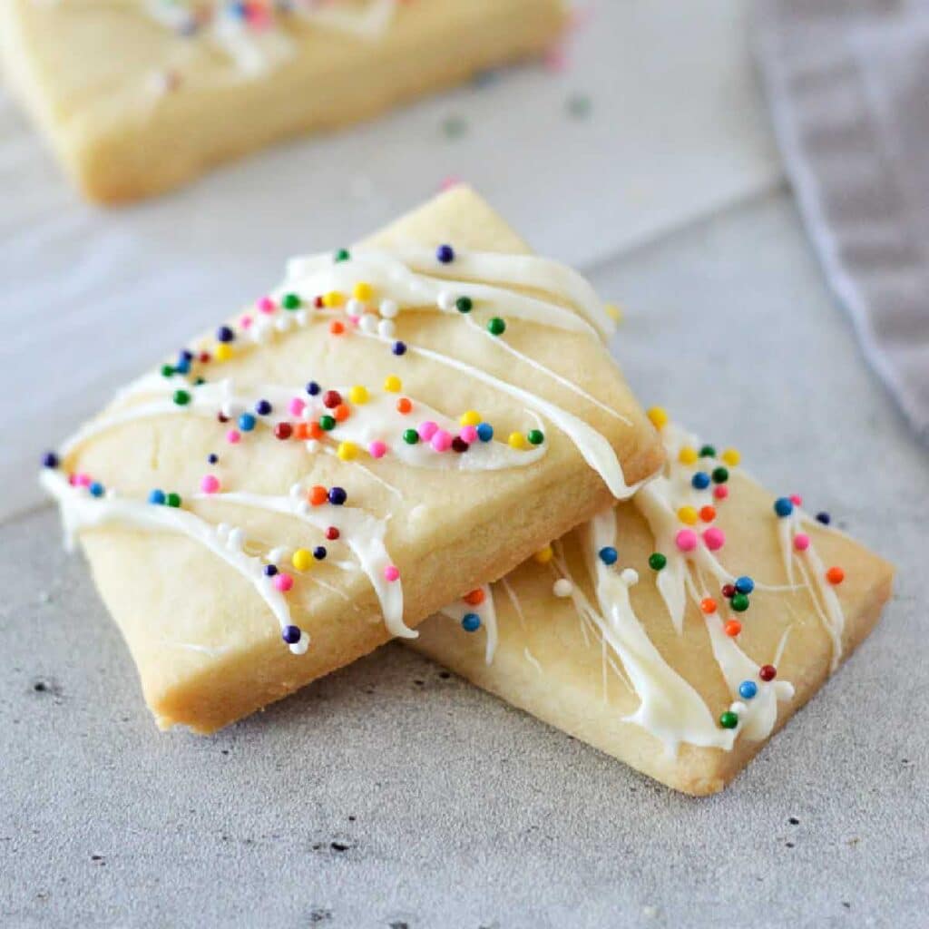 two eggless butter cookies stacked on each other with sprinkles on top.