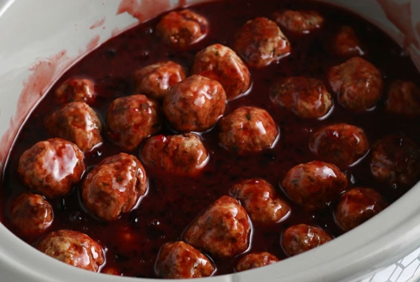 Close up of slow cooker filled with grape jelly meatballs and barbecue sauce.