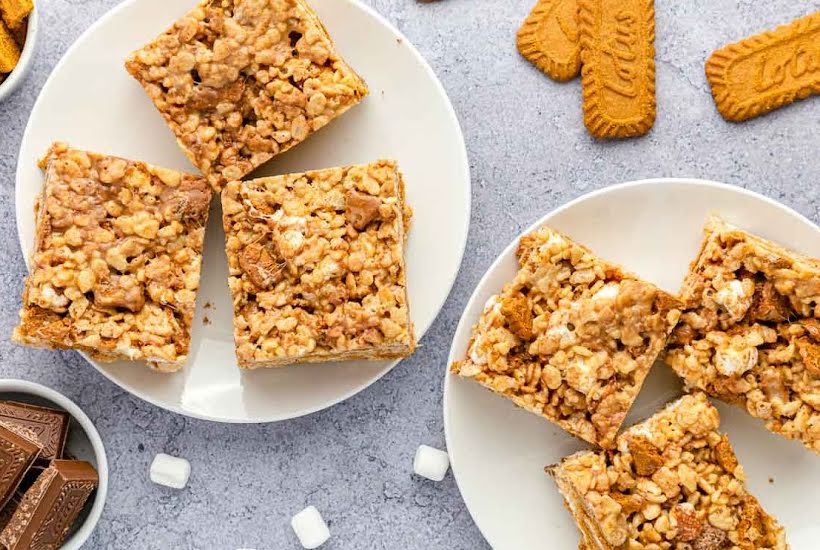 Two white plates filled with squares of no bake Biscoff Rice Krispie treats.